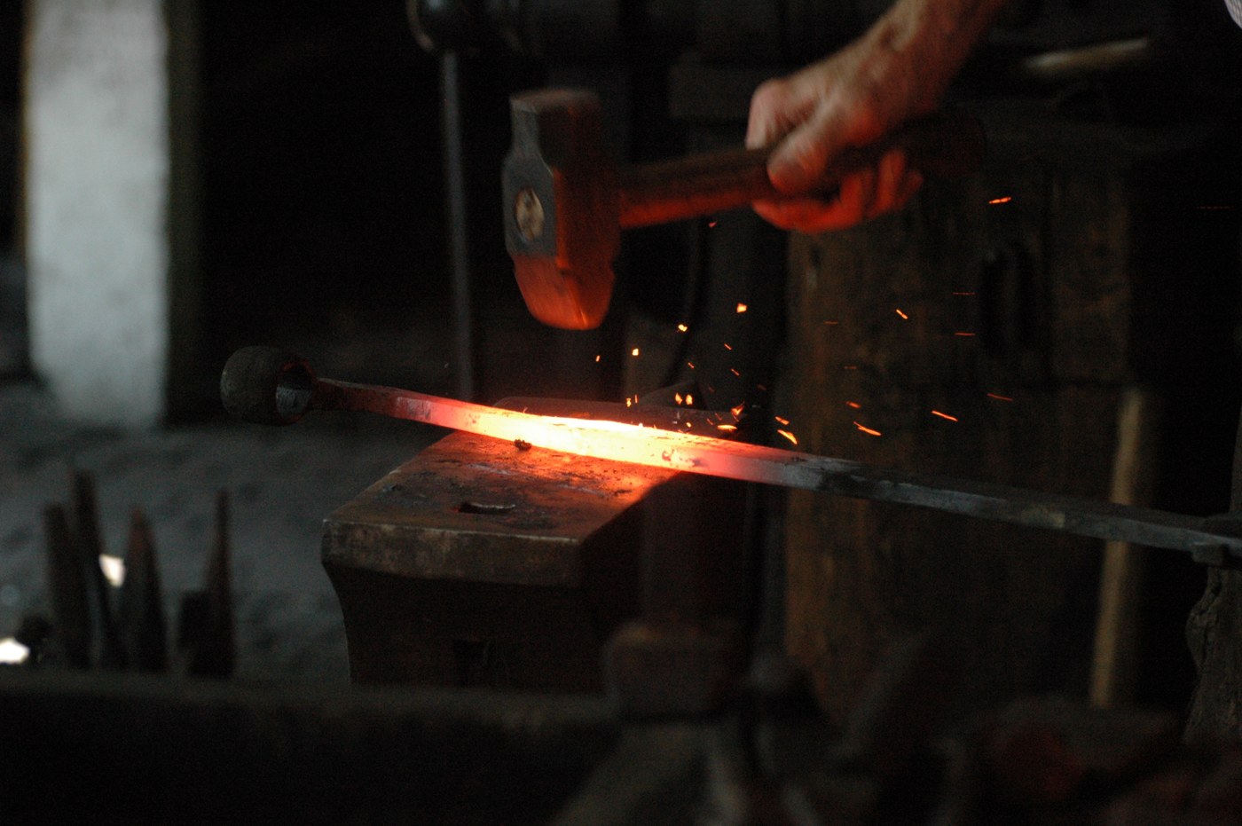 Kalvis apdirba įkaitintą metalą ant priekalo.