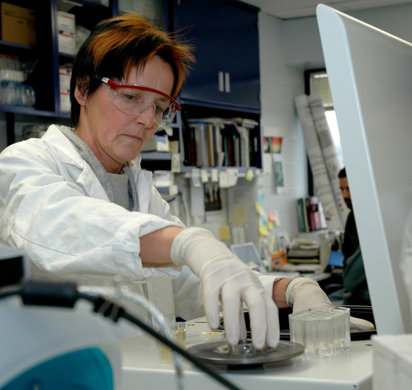 Mokslininkė deda mėginius į centrifugą NCI laboratorijoje.